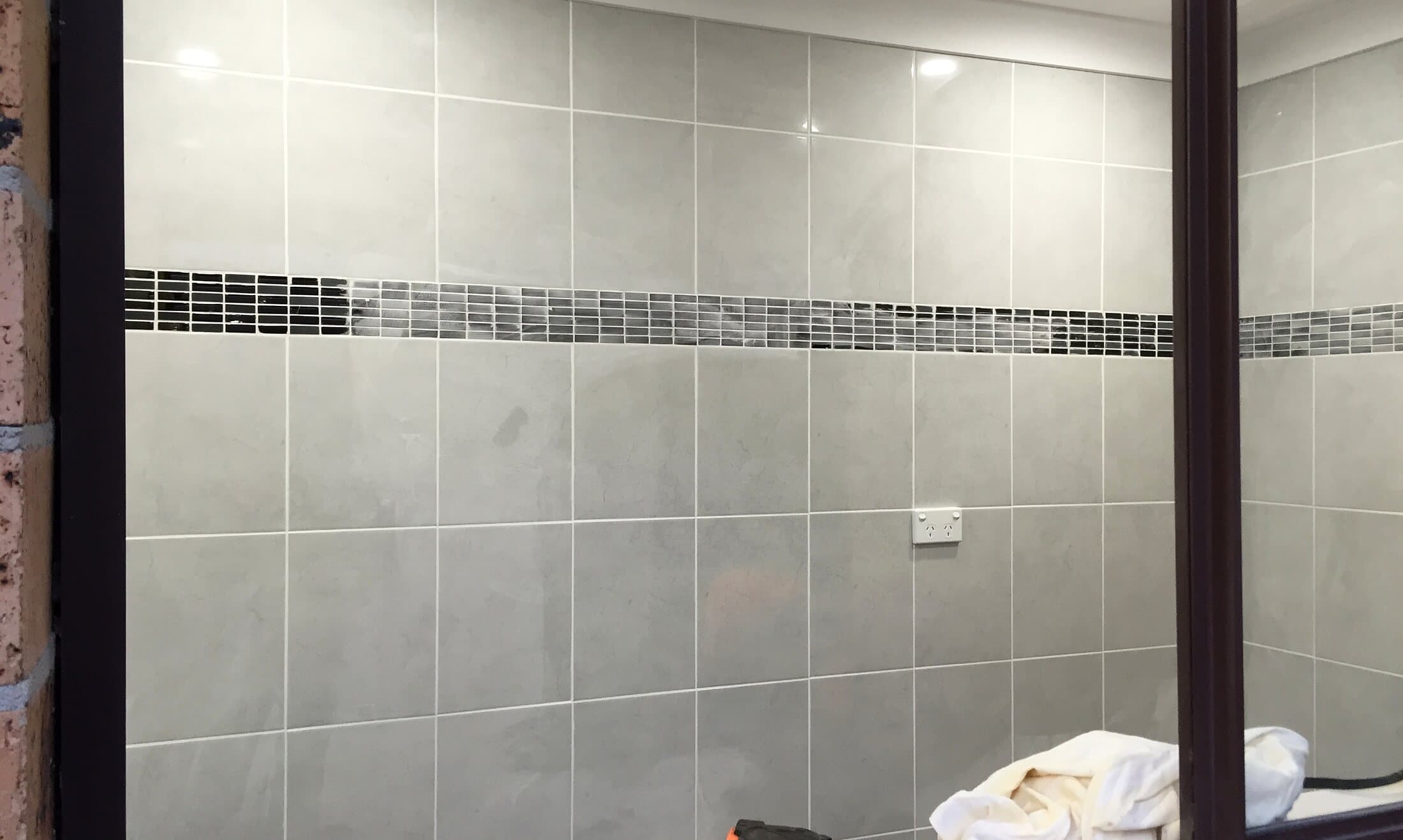 Newly tiled bathroom walls with a mosaic feature strip