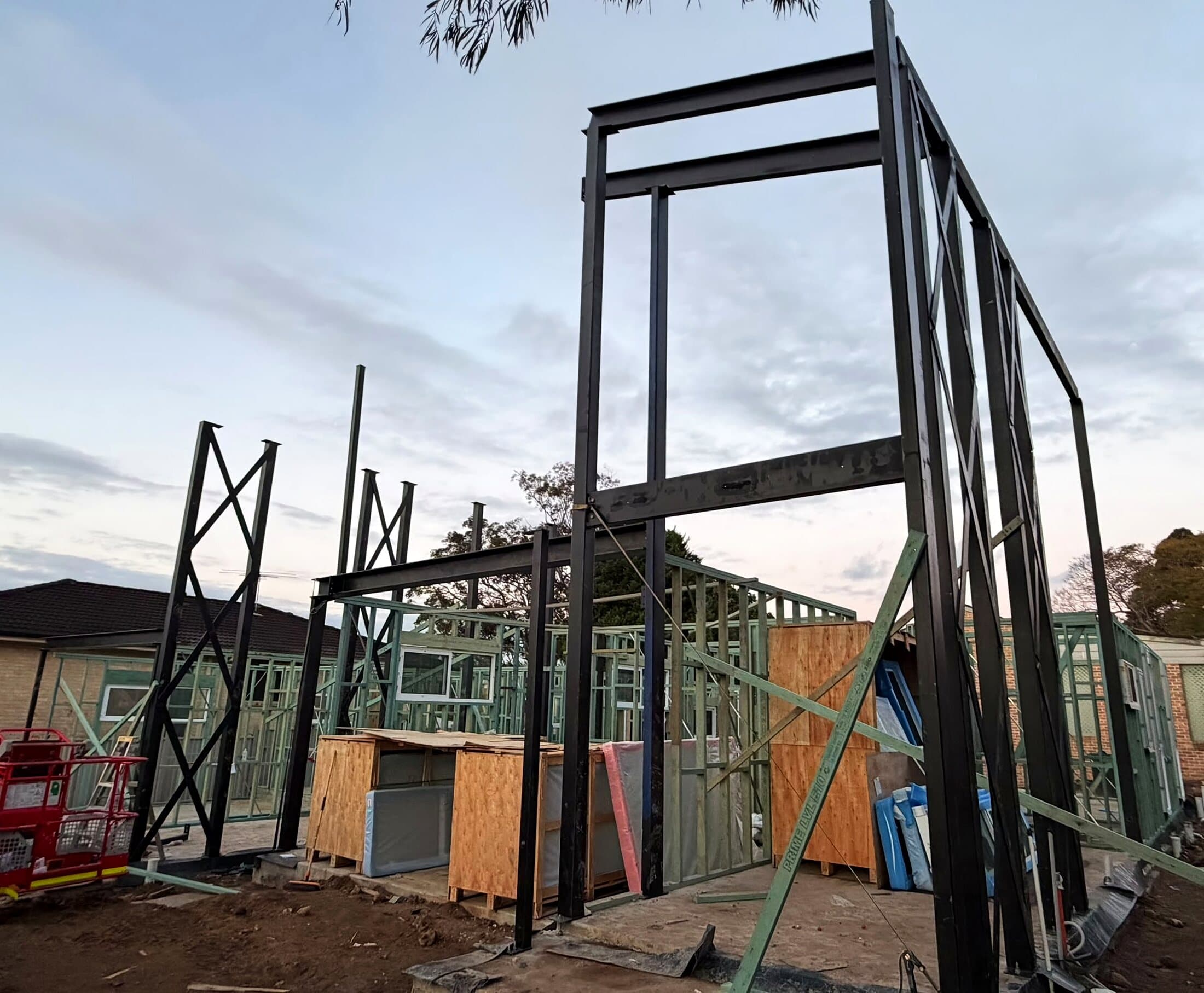 Structural steel frame standing on a residential site at dusk